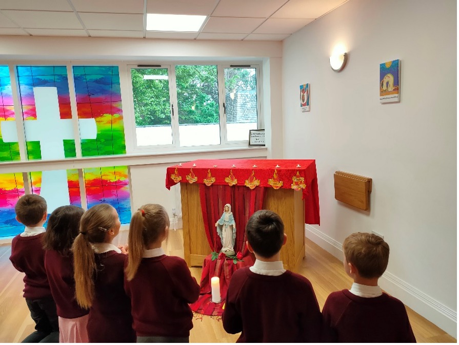 CCPS – Bournemouth – Pupils Praying A picture of a few children knelling down before an altar.