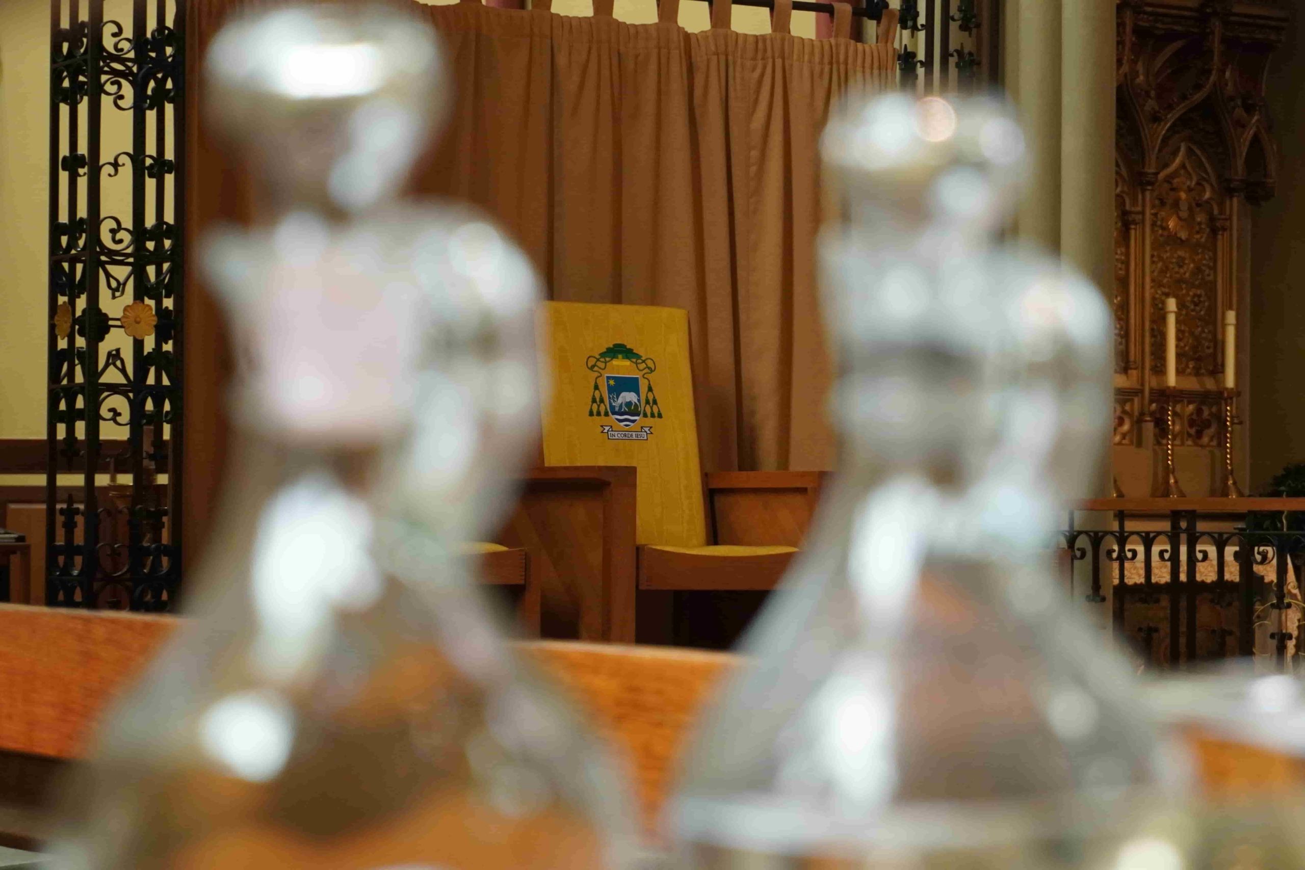 The Bishop of Portsmouth's chair. A yellow chair with the Diocese of Portsmouth crest in the middle of two glass bottles.